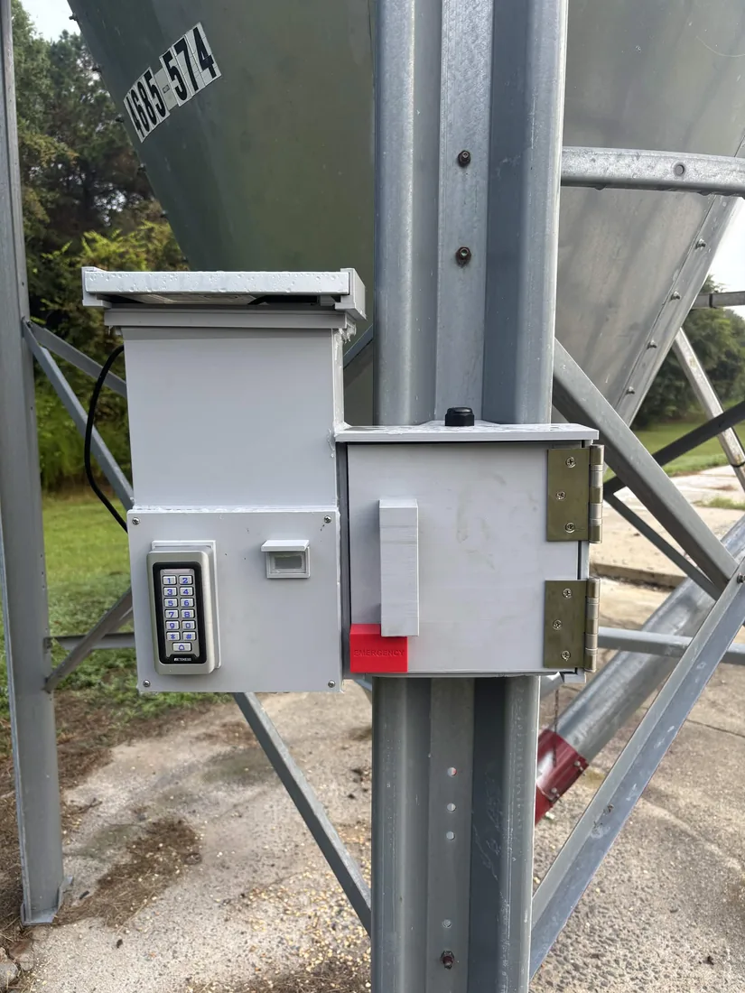 The One Latch beta unit bolted to a feed bin leg: keypad, display window, solar top and the emergency release cap